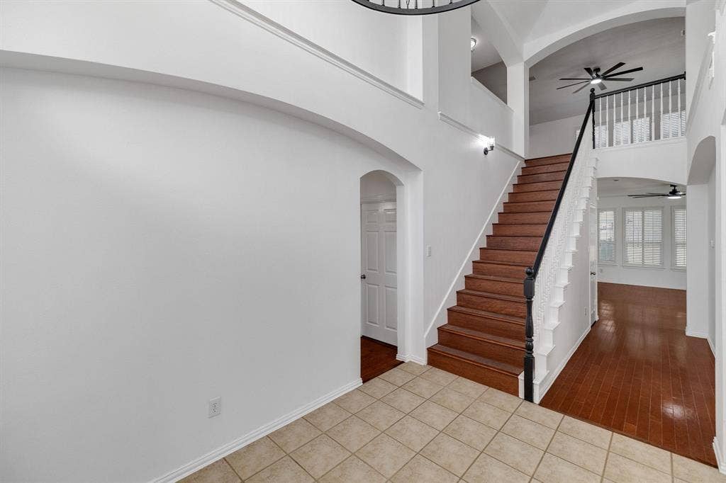 239 Glen Ridge Drive, Murphy, TX 75094 Tiled entry with wood-finish flooring, staircase with dark wood-finish handrail, and arched doorways
