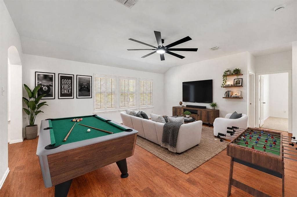 239 Glen Ridge Drive, Murphy, TX 75094 Spacious living area featuring wood-finish flooring, multiple windows with plantation shutters, a ceiling fan, and built-in floating shelves