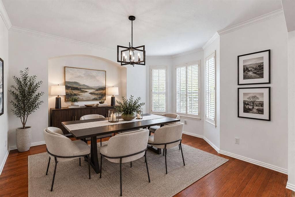 239 Glen Ridge Drive, Murphy, TX 75094 Hardwood flooring, arched wall niche, bay window with plantation shutters, crown molding, and a contemporary chandelier