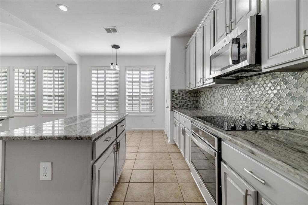 239 Glen Ridge Drive, Murphy, TX 75094 Kitchen featuring light-toned cabinetry, a stainless steel microwave, a built-in cooktop, and a distinct mosaic tile backsplash