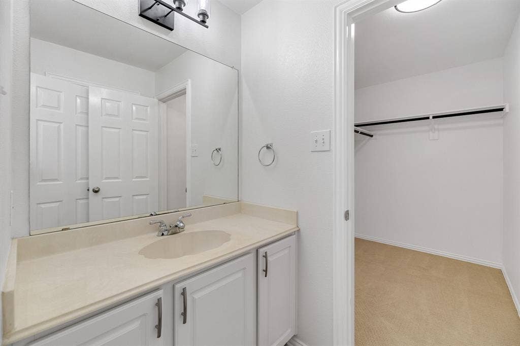 239 Glen Ridge Drive, Murphy, TX 75094 Vanity with integrated sink, chrome faucet, and white cabinetry