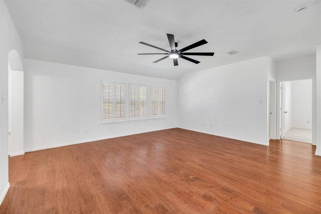 239 Glen Ridge Drive, Murphy, TX 75094 Vaulted ceiling with a contemporary ceiling fan, wood-finish flooring, and multiple windows with plantation shutters