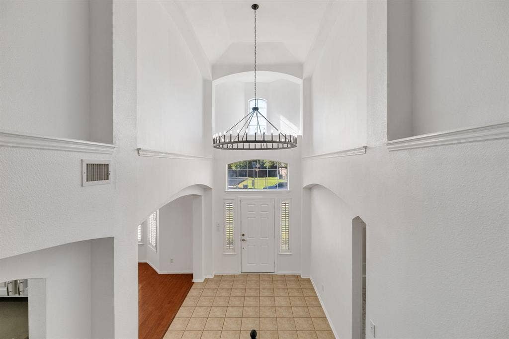 239 Glen Ridge Drive, Murphy, TX 75094 Two-story foyer with a vaulted ceiling, prominent chandelier, arched doorway, and tile flooring