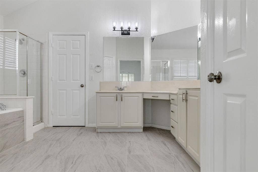 239 Glen Ridge Drive, Murphy, TX 75094 Dual vanity with integrated sink, glass-enclosed shower, built-in bathtub with tiled surround, wood-finish flooring, and vanity lighting