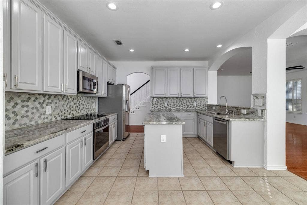 239 Glen Ridge Drive, Murphy, TX 75094 Kitchen featuring light-toned cabinetry, light-toned countertops, stainless steel appliances, a mosaic tile backsplash, and ceramic tile flooring