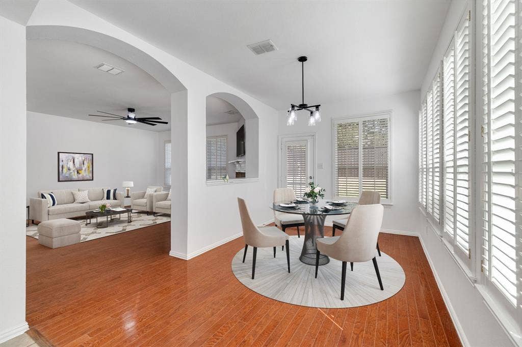 239 Glen Ridge Drive, Murphy, TX 75094 Arched doorways, wood-finish flooring, white plantation shutters, built-in ceiling fan, and a modern chandelier