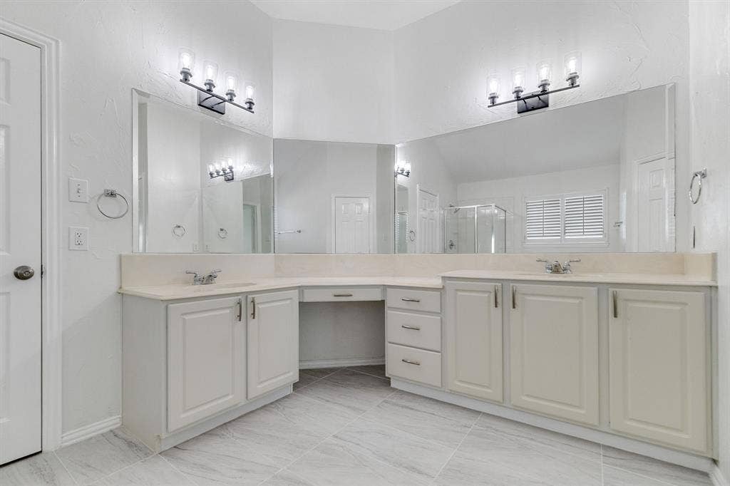 239 Glen Ridge Drive, Murphy, TX 75094 Dual vanity with light-toned countertops, white cabinetry, expansive mirrors, and decorative light fixtures