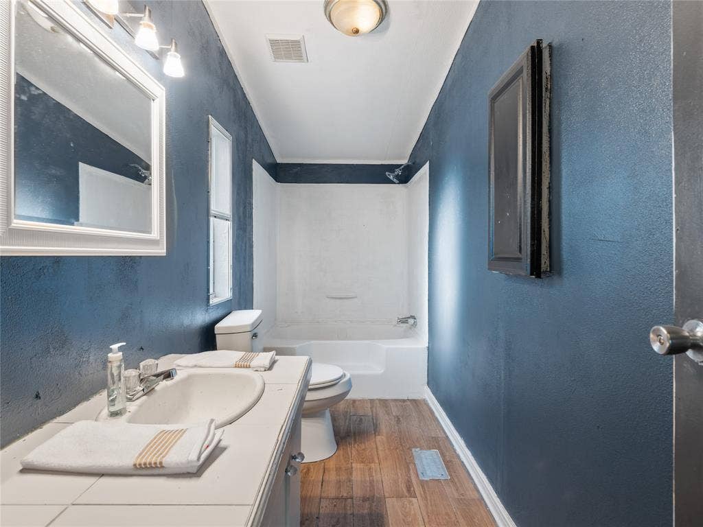 Bathroom featuring a single vanity, wood-finish flooring, and a shower-tub combination