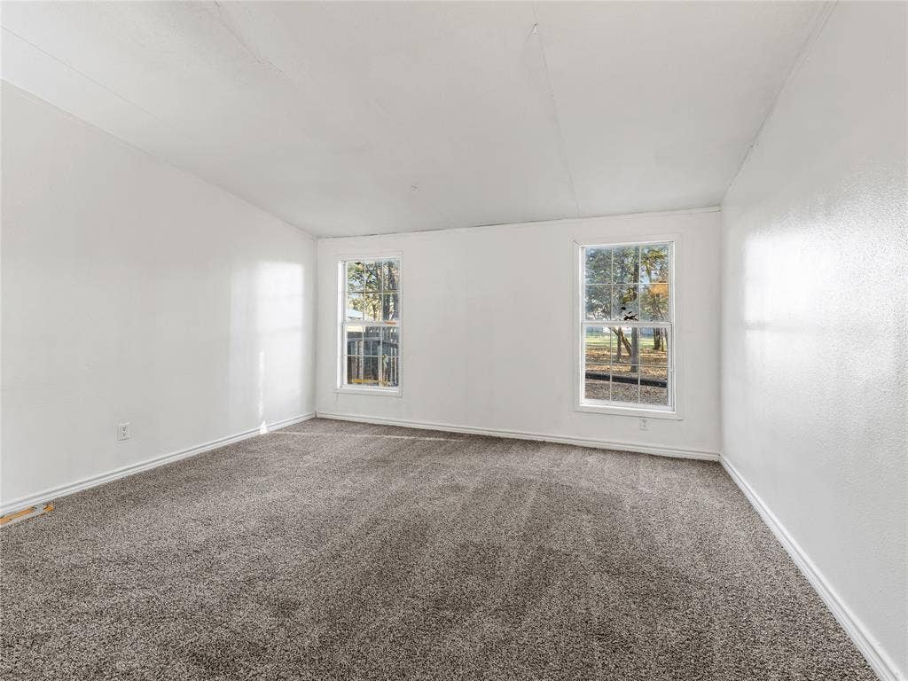 Light-filled interior featuring two windows, neutral wall finishes, and gray carpeting