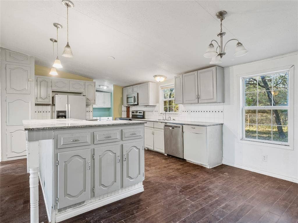 Kitchen with a central island, stainless steel appliances, and white cabinetry