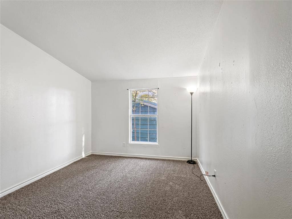 Carpeted flooring, single pane window, and white walls