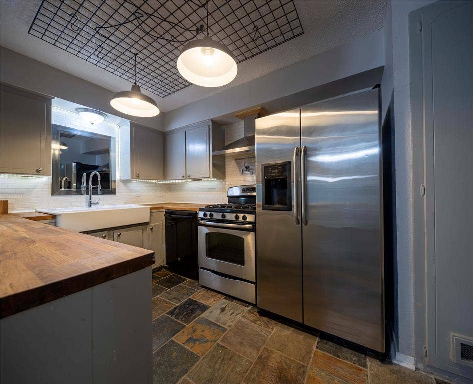 1717 N Locust Street, #1, Denton, TX 76201 Kitchen featuring slate tile flooring, wood-finish countertops, undermount farmhouse sink, stainless steel appliances, and integrated ceiling lighting