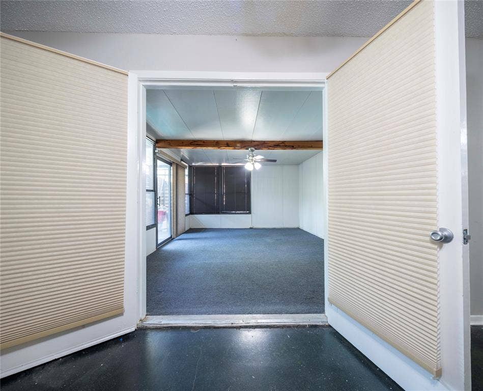 1717 N Locust Street, #1, Denton, TX 76201 Room with dark carpeting, exposed wood beam, ceiling fan with light fixture, and sliding glass doors with dark screens