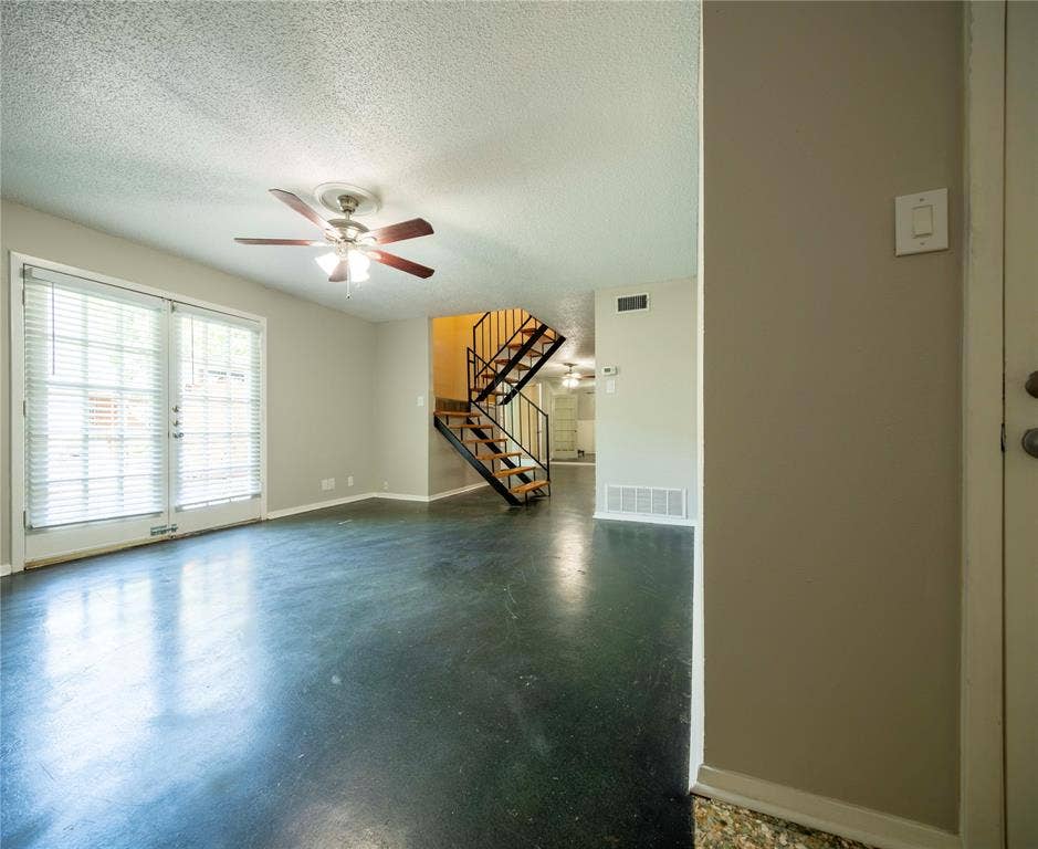 1717 N Locust Street, #1, Denton, TX 76201 French doors with blinds, ceiling fan with light fixture, open-tread staircase with metal railing, dark-toned flooring, light-colored walls