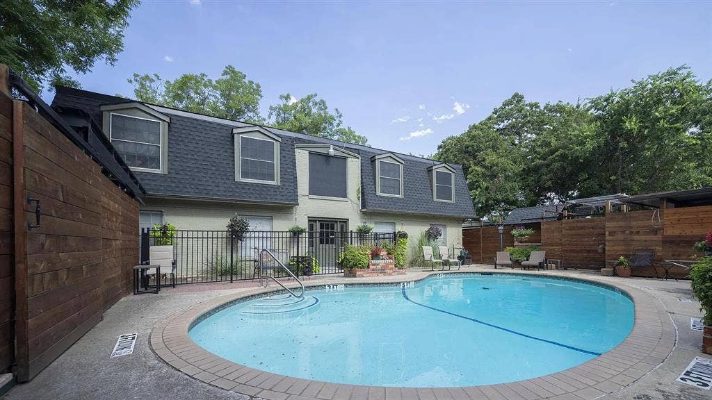1717 N Locust Street, #1, Denton, TX 76201 Oval-shaped swimming pool with concrete decking, surrounded by a wrought-iron fence and wood privacy fencing