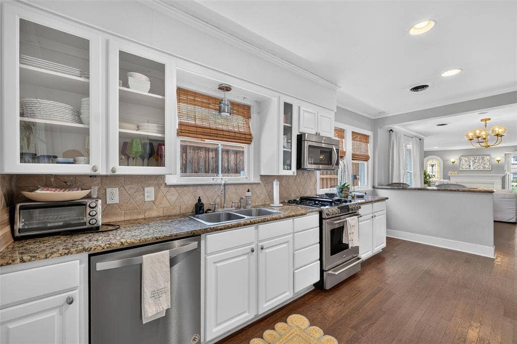 5630 Vanderbilt Avenue, Dallas, TX 75206 White cabinetry with glass-front uppers, stainless steel appliances, granite countertops, and wood-finish flooring