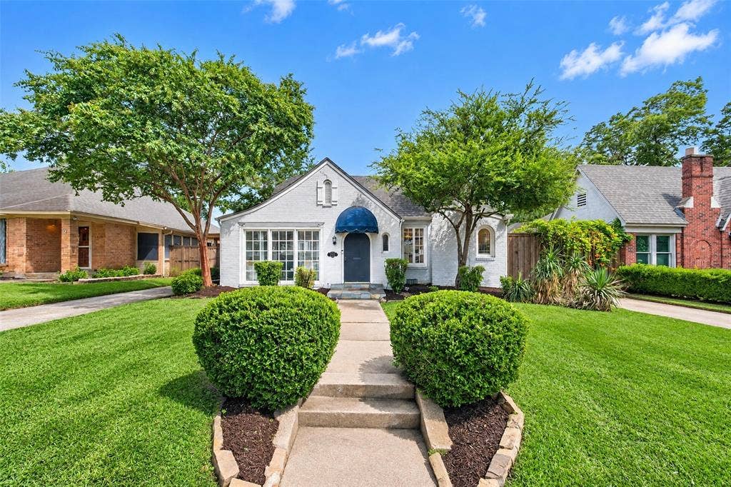 5630 Vanderbilt Avenue, Dallas, TX 75206 White stucco exterior with a dark blue awning, multiple paned windows, and a concrete pathway