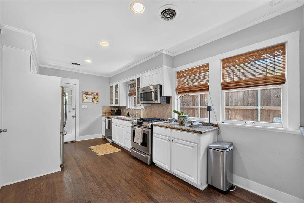 5630 Vanderbilt Avenue, Dallas, TX 75206 White cabinetry with stainless steel appliances, wood-finish flooring, recessed lighting, and crown molding