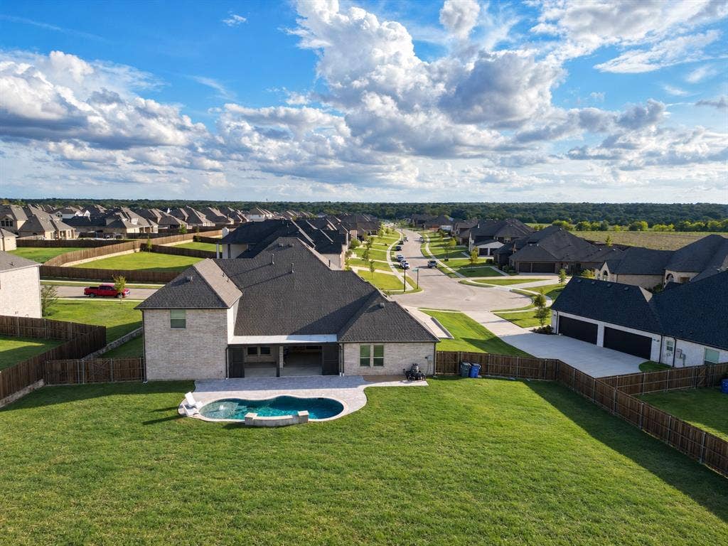 Exterior featuring a brick and composite shingle roof structure, covered rear patio, in-ground swimming pool with stone coping, and fenced backyard