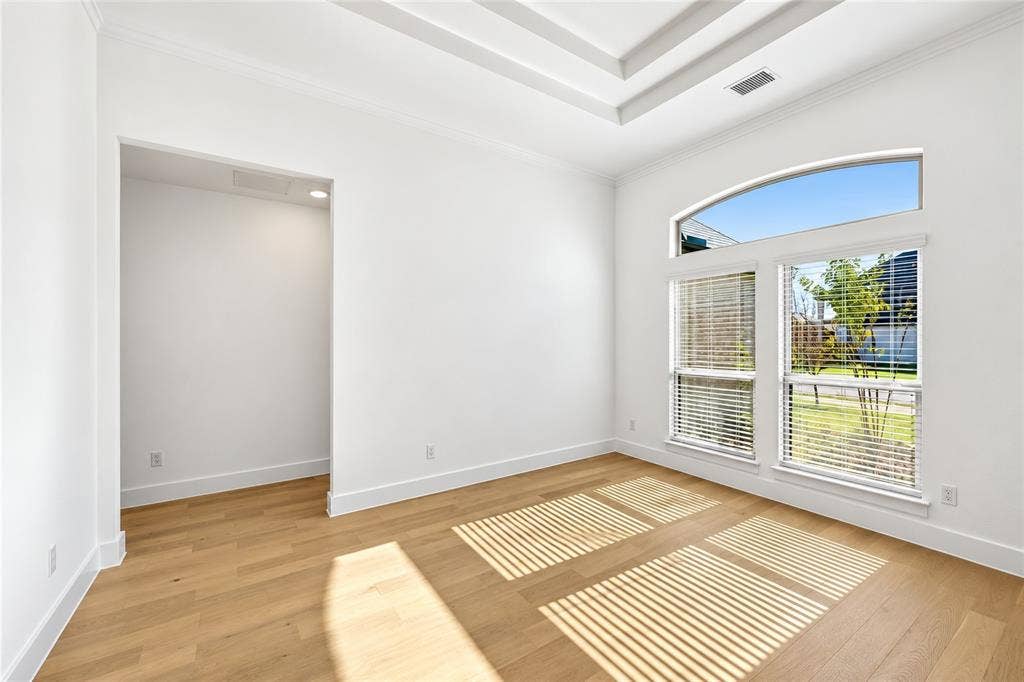 Formal Dining Room with Tray ceiling, light-toned wood-finish flooring, and expansive windows featuring an arched transom