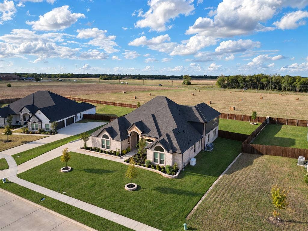 Single-story masonry residence featuring an asphalt shingle roof, arched entryway, concrete driveway, and a fenced backyard with landscaped lawn