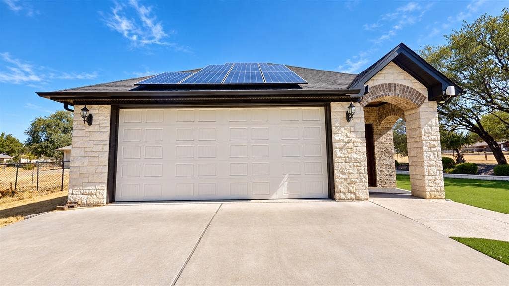 1729 Bent Tree Court, Granbury, TX 76049 Detached 2-car garage with epoxy flooring, half bathroom, screened garage door, and window AC unit