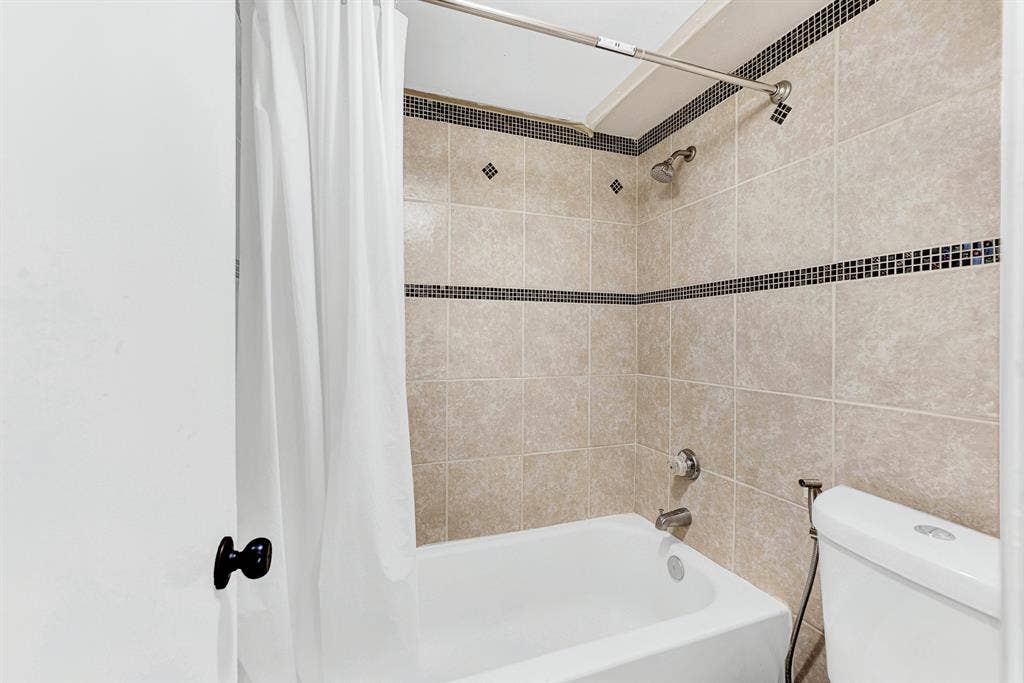 108 Kingsbridge Drive, Garland, TX 75040 Expansive backyard with a full privacy fence, mature trees, brick exterior, and a stone retaining wall