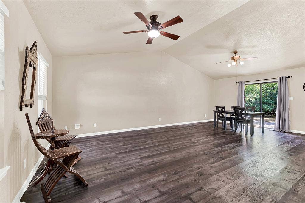 108 Kingsbridge Drive, Garland, TX 75040 Vaulted ceiling with dual ceiling fans, wood-finish flooring, and sliding glass door access to the outdoors