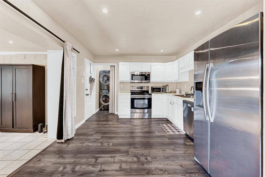 108 Kingsbridge Drive, Garland, TX 75040 Wood-finish flooring, white cabinetry, stainless steel appliances, recessed lighting, and a stacked washer/dryer
