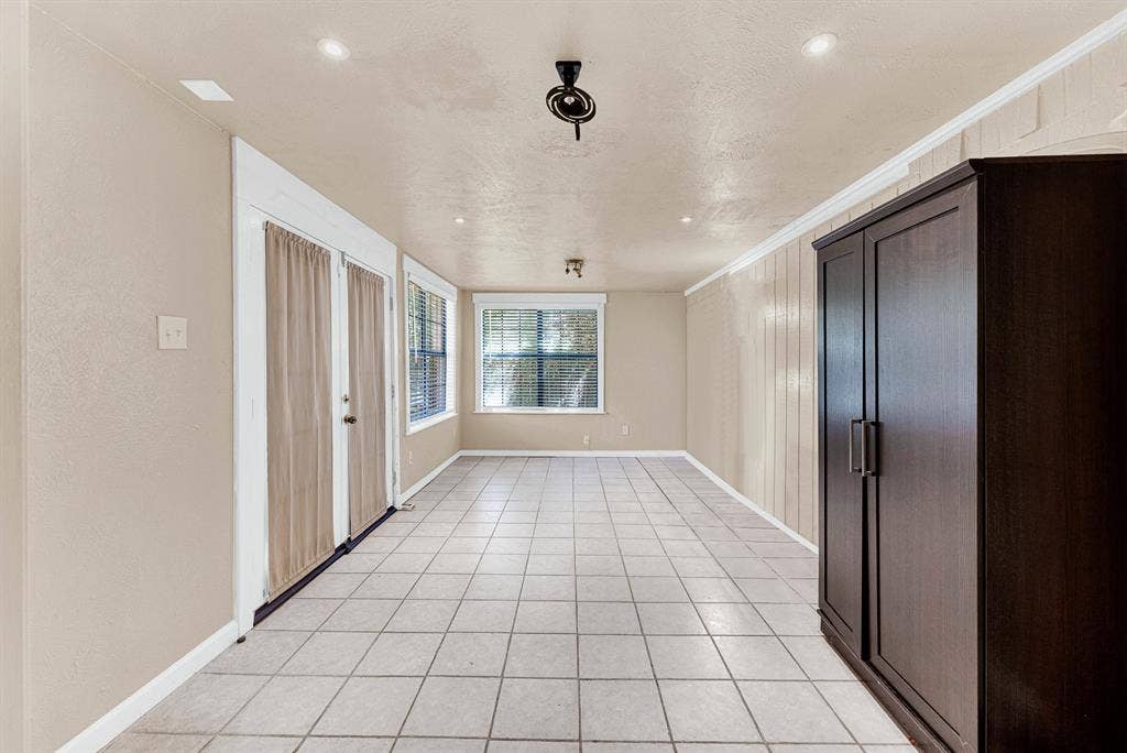 108 Kingsbridge Drive, Garland, TX 75040 Tiled flooring, built-in shelving, painted brick accent wall, recessed lighting, and crown molding