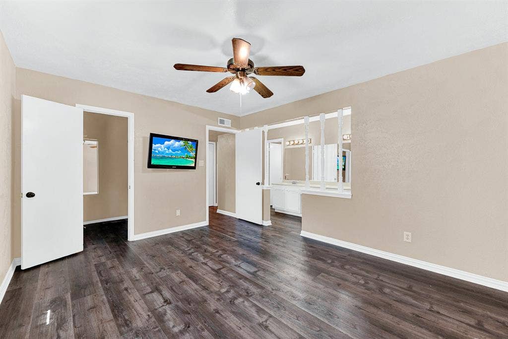 108 Kingsbridge Drive, Garland, TX 75040 Wood-finish flooring, ceiling fan with light fixture, wall-mounted television, and a half-wall with decorative dividers