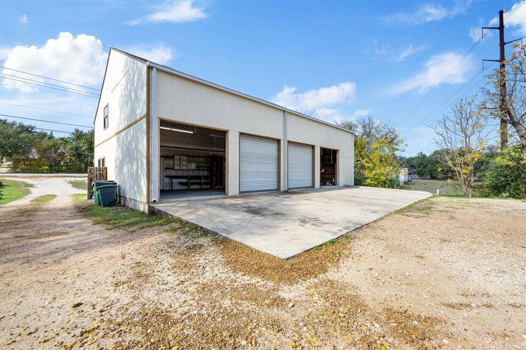 5205 Hudson Bend Road, Austin, TX 78734 Metal-sided outbuilding featuring multiple bay doors and a concrete pad