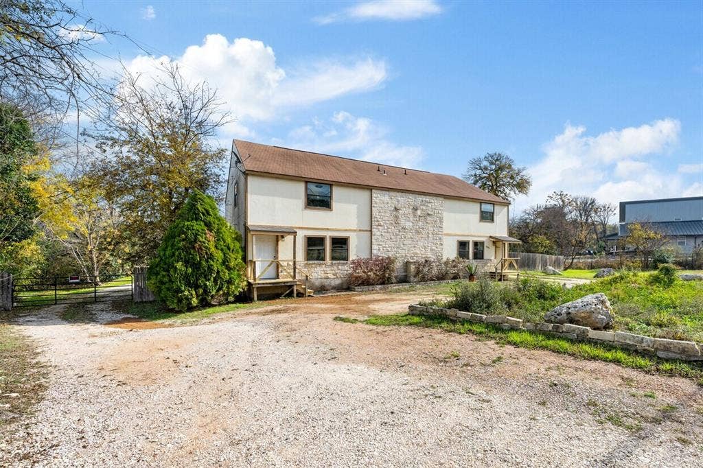 5205 Hudson Bend Road, Austin, TX 78734 Two-story exterior with stone and siding facade, covered entryways, and a gravel drive