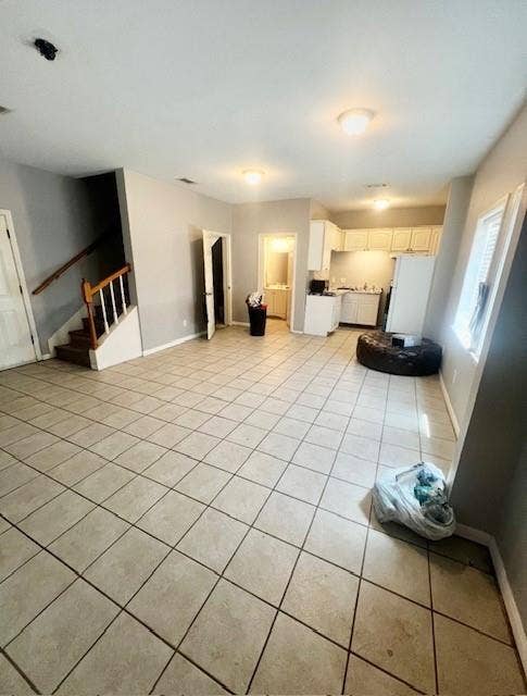 5205 Hudson Bend Road, Austin, TX 78734 Expansive main living area with neutral-toned tile flooring throughout, featuring a staircase with wood railings, a kitchen with white cabinetry, and a bathroom with a vanity and mirror