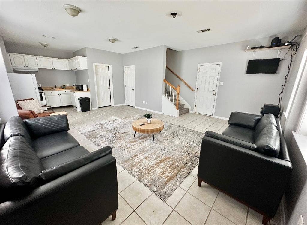 5205 Hudson Bend Road, Austin, TX 78734 Open-concept common area featuring tile flooring, white kitchen cabinetry, and a staircase with wood handrails