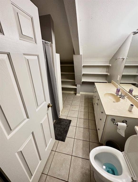 5205 Hudson Bend Road, Austin, TX 78734 Bathroom featuring a double vanity, built-in shelving, tiled flooring, and a paneled door
