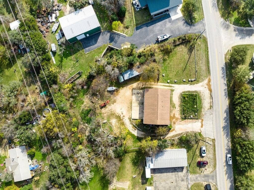 5205 Hudson Bend Road, Austin, TX 78734 Property featuring a main building with a brown roof, an adjacent green-roofed structure, and a rectangular grass area