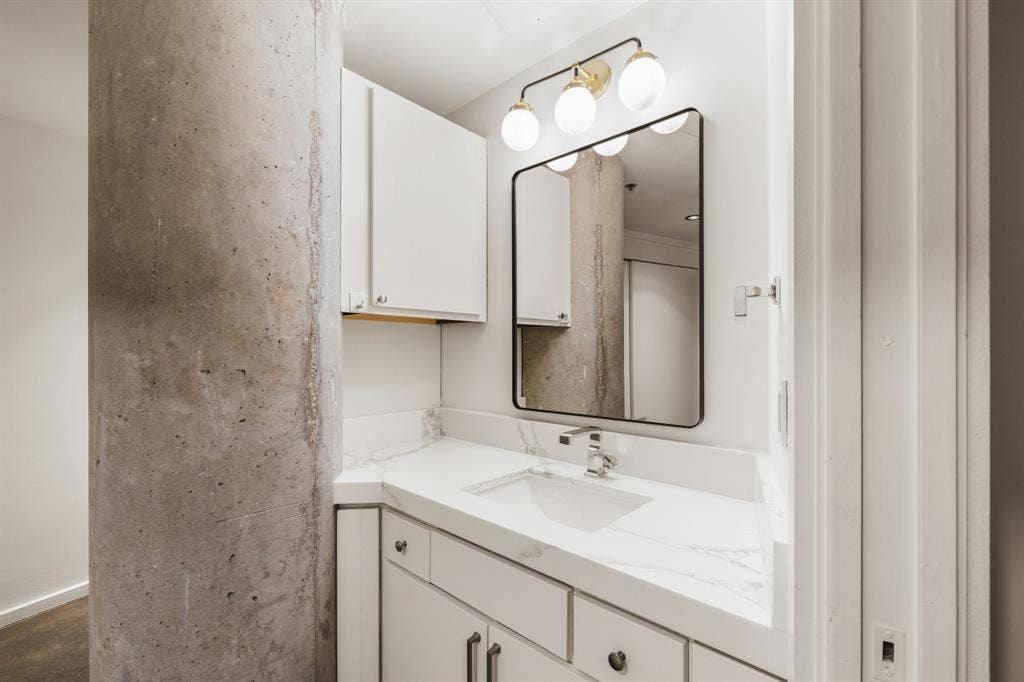 White vanity with a rectangular undermount sink, a chrome faucet, and white countertops