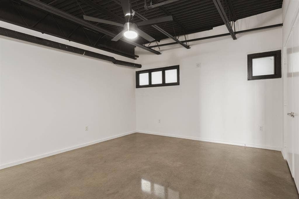 Exposed black ceiling joists, concrete flooring, and multiple high windows