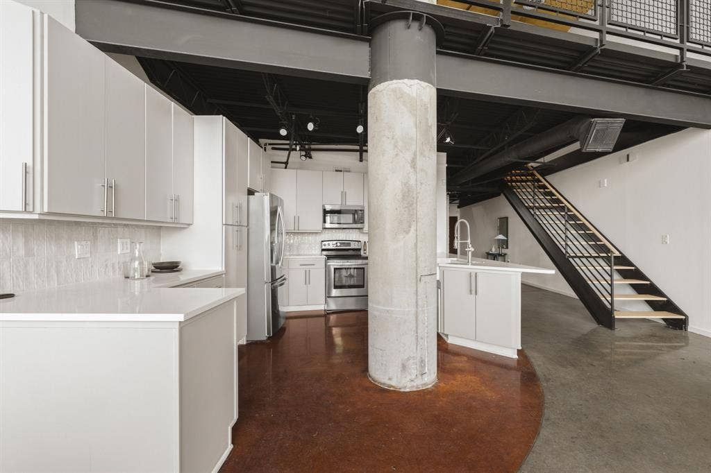 Open-concept kitchen with light cabinetry, stainless steel appliances, and solid surface countertops
