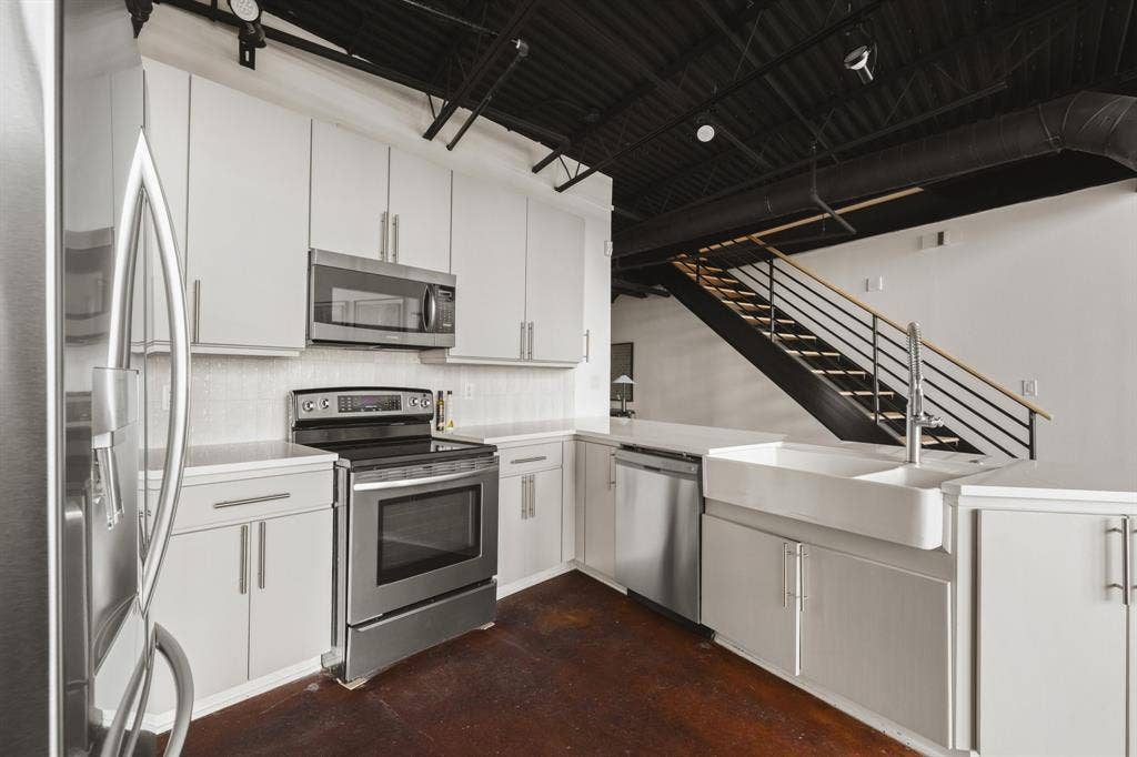 Kitchen featuring stainless steel appliances, white cabinetry, a farmhouse sink, and a white countertop