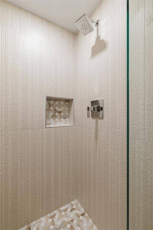Shower featuring textured wall tile, mosaic tile shower floor, mosaic tile shower niche, and a rain shower head