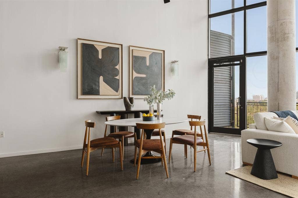Polished concrete flooring, floor-to-ceiling windows, high ceilings, a balcony with metal railing, and a concrete support column