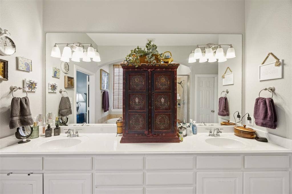 1000 Fenwick Lane, Forney, TX 75126 Dual undermount sinks, white countertop, extensive vanity mirror, wall-mounted light fixtures, and white cabinetry