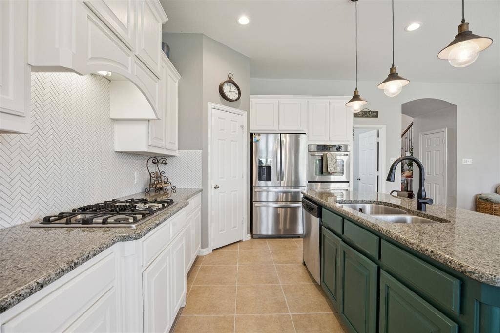 1000 Fenwick Lane, Forney, TX 75126 Kitchen featuring white shaker-style cabinetry, a herringbone pattern tile backsplash, a built-in gas cooktop, stainless steel appliances, and a central island with a double basin sink
