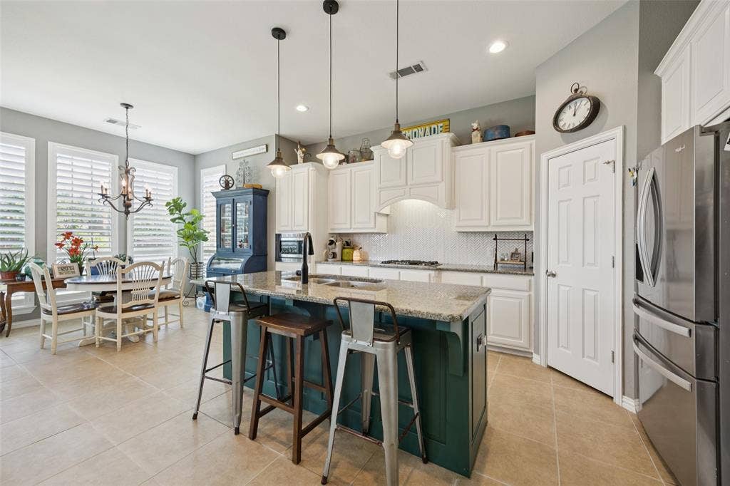 1000 Fenwick Lane, Forney, TX 75126 Kitchen with an island featuring a granite countertop, white cabinetry, and a tile backsplash