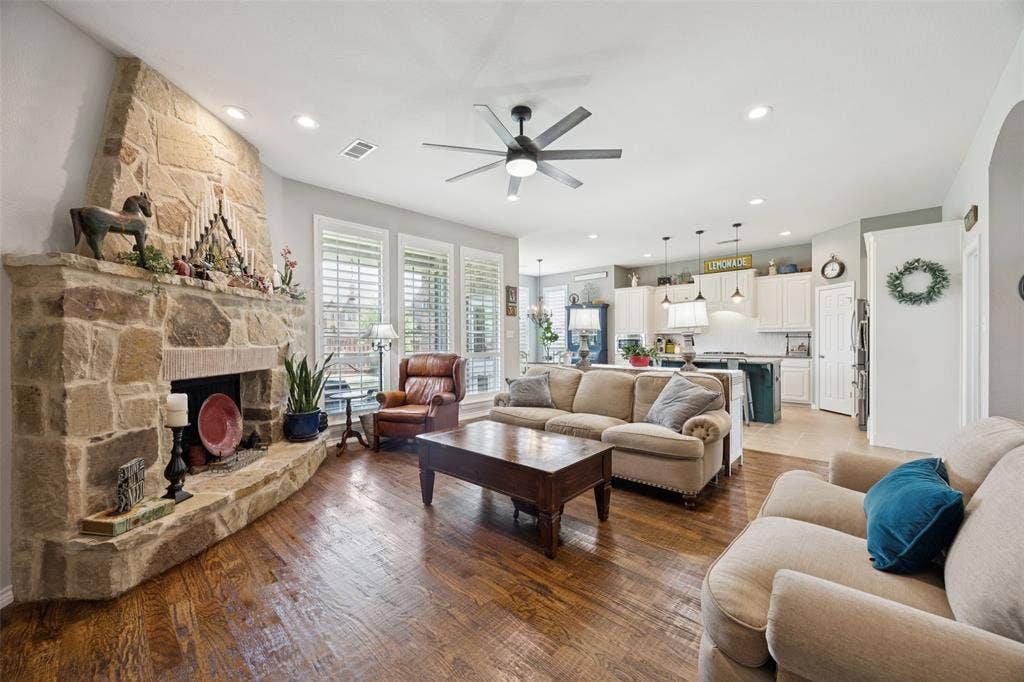 1000 Fenwick Lane, Forney, TX 75126 Stone fireplace, wood-finish flooring, recessed lighting, ceiling fan, and white plantation shutters