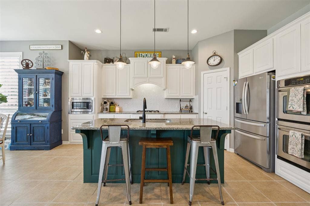 1000 Fenwick Lane, Forney, TX 75126 Kitchen featuring a central island with countertop seating, stainless steel appliances, white cabinetry, and recessed lighting