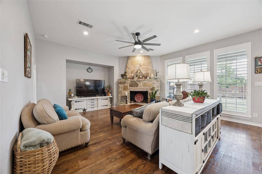 1000 Fenwick Lane, Forney, TX 75126 Stone-faced fireplace, wood-finish flooring, recessed lighting, ceiling fan, and multiple windows with plantation shutters