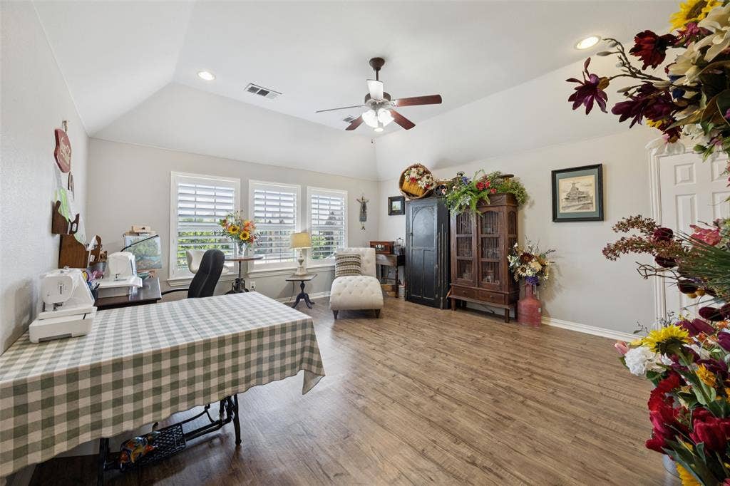 1000 Fenwick Lane, Forney, TX 75126 Wood-finish flooring, vaulted ceiling, recessed lighting, ceiling fan, and multiple windows with plantation shutters